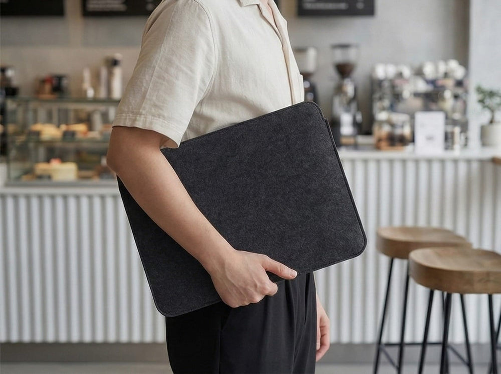 Person holding Orgemy felt laptop case under arm, showing slim profile.